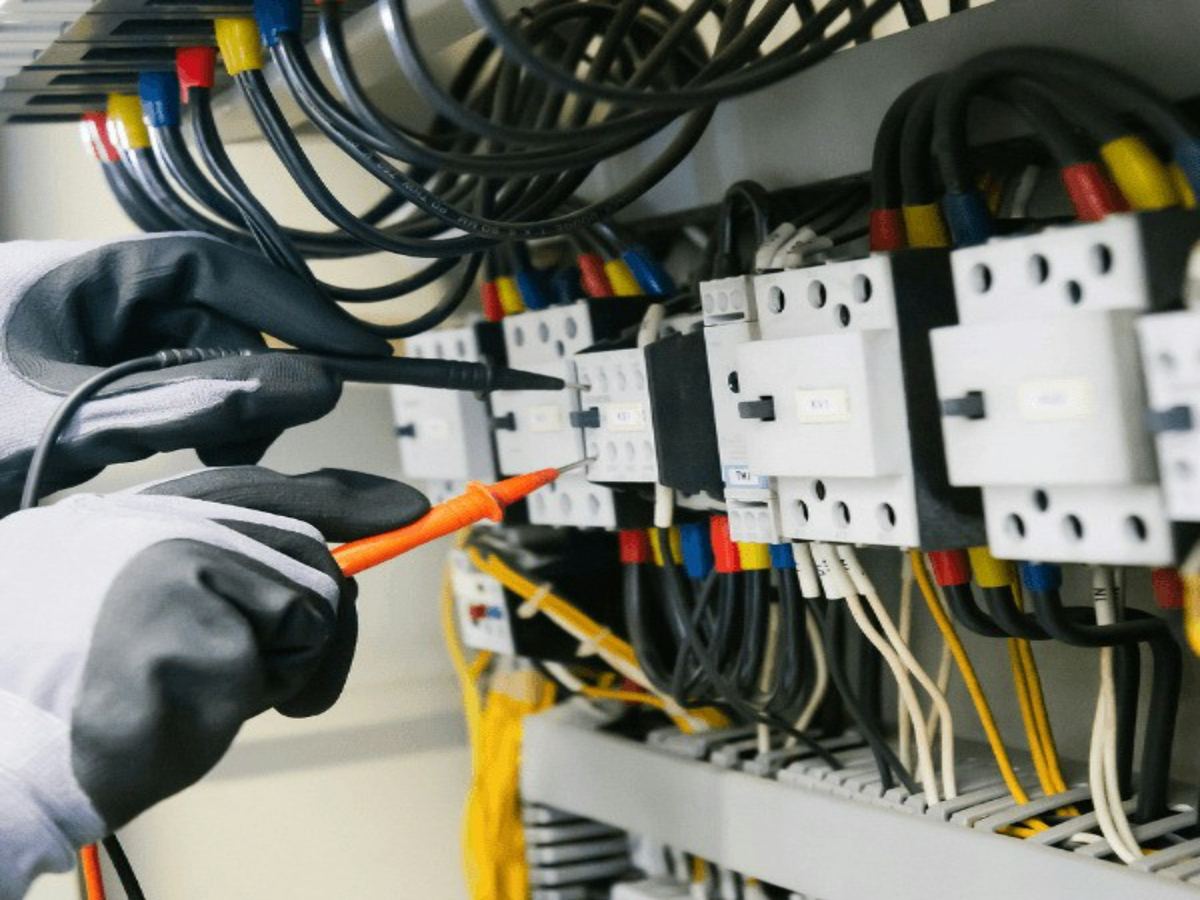 Electrician testing terminals in an electrical panel with a meter probe
