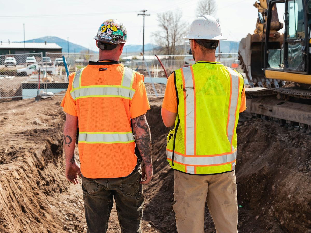 Two field personnel in high-visibility PPE coordinating on site