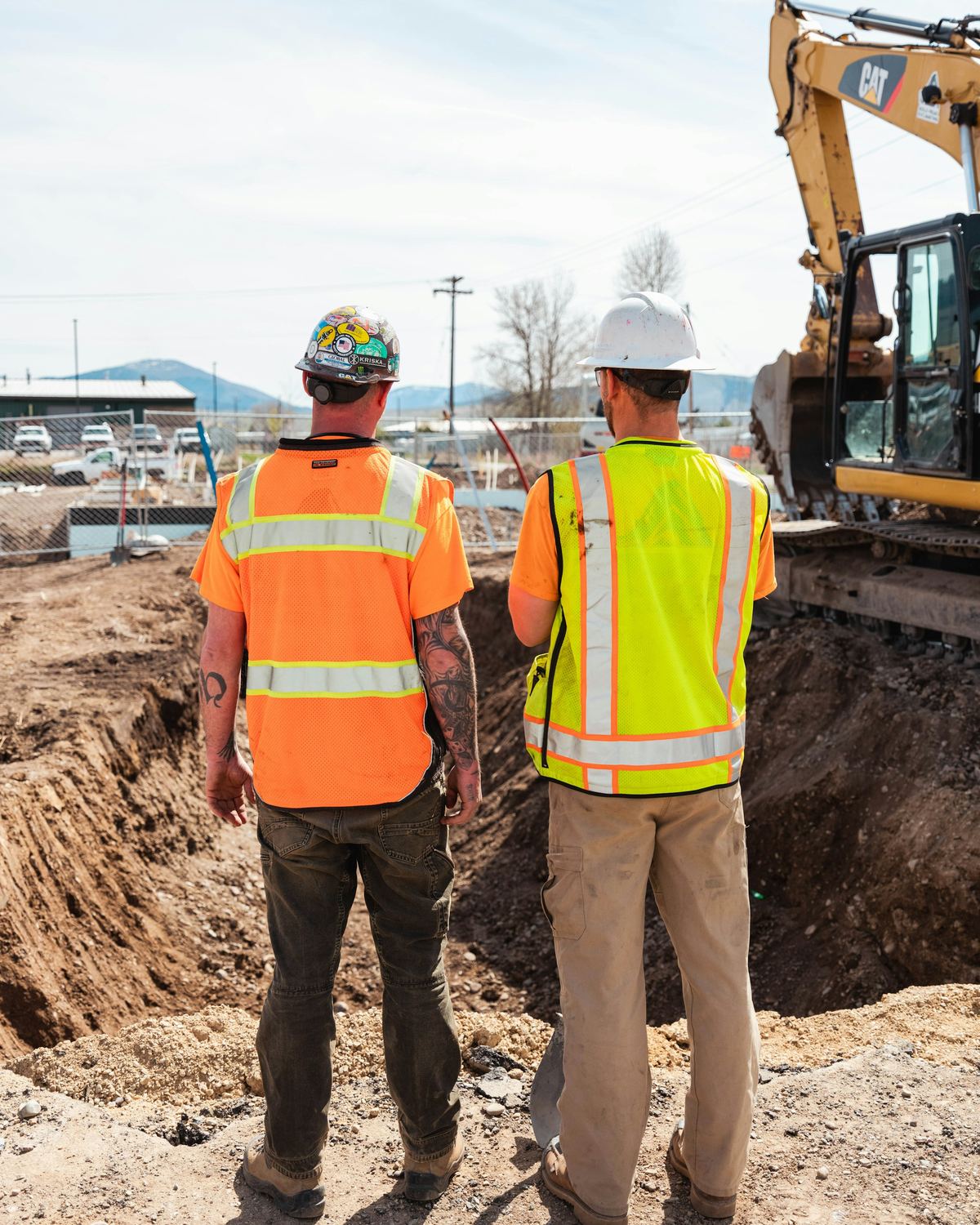 Two workers in high-visibility vests and hard hats
