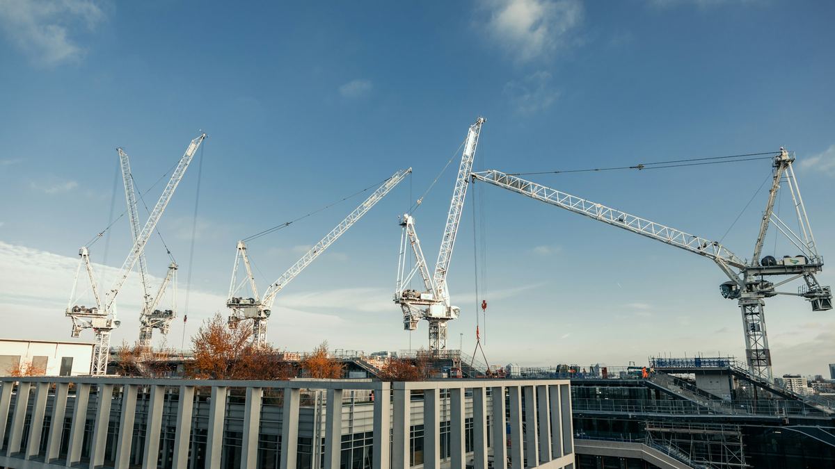 Tower cranes above a large commercial building under construction