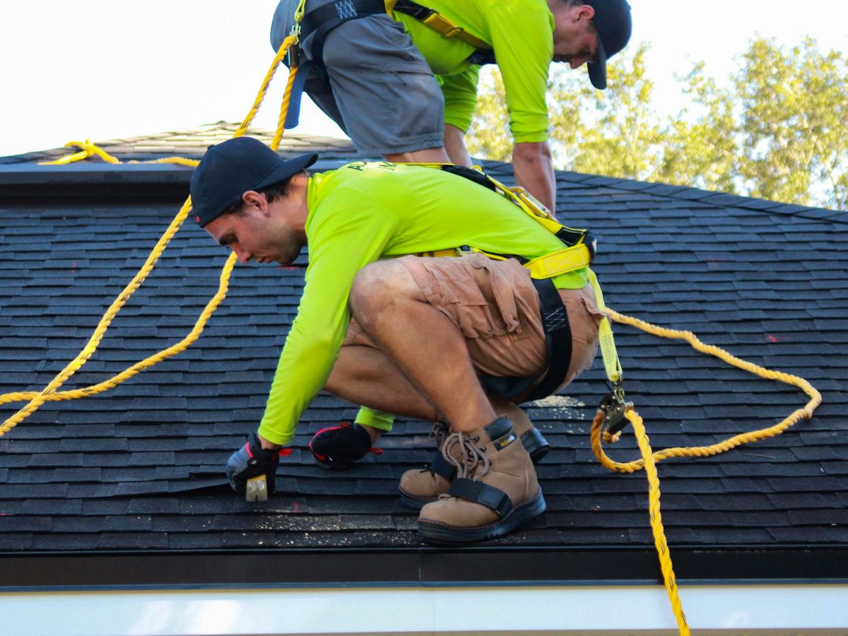 Residential roof under construction with crew members using fall protection